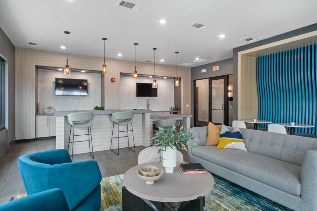 Clubhouse lounge with sofas, TVs, and kitchenette